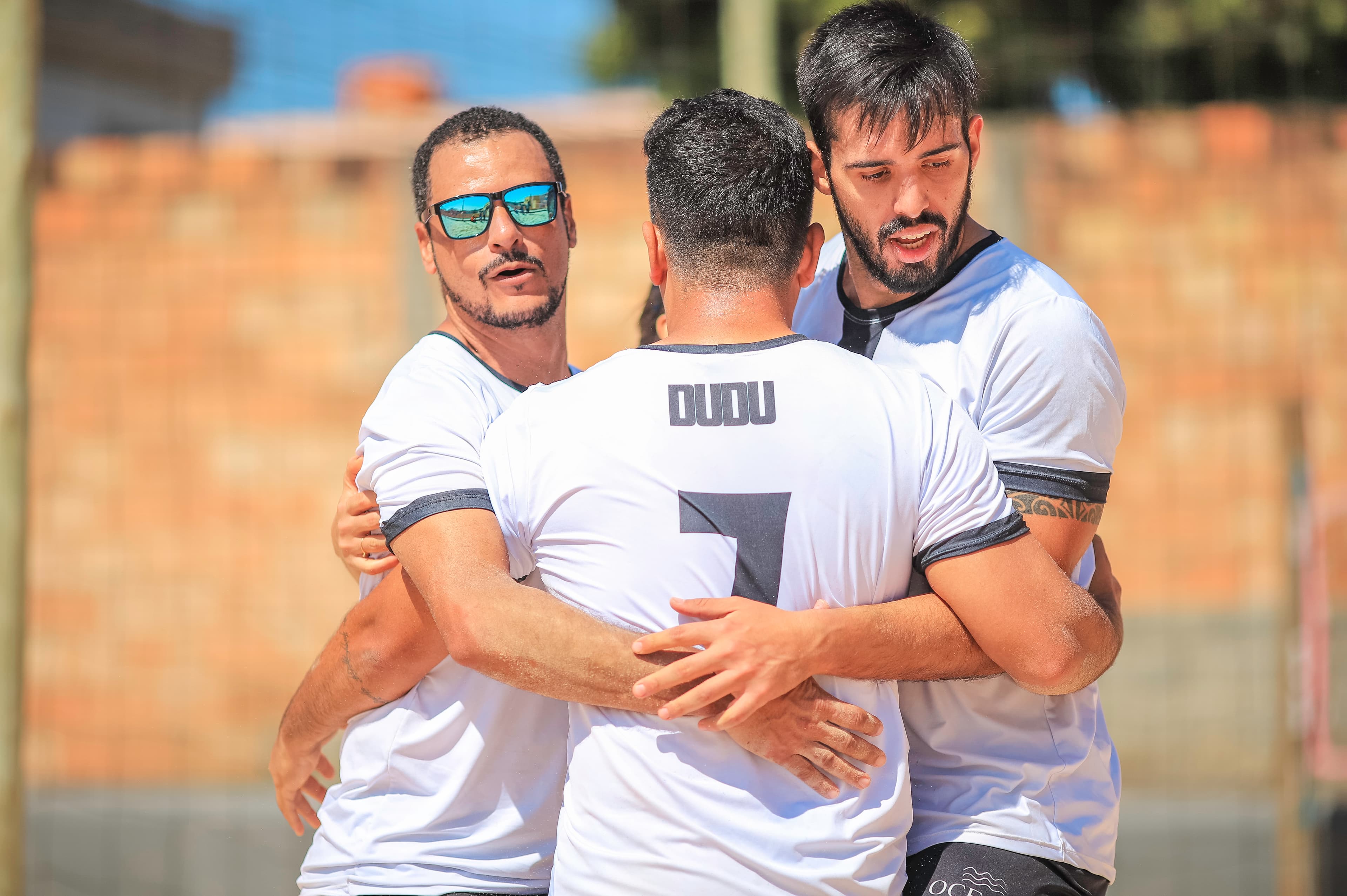 Atletas se abraçando durante partida de areia