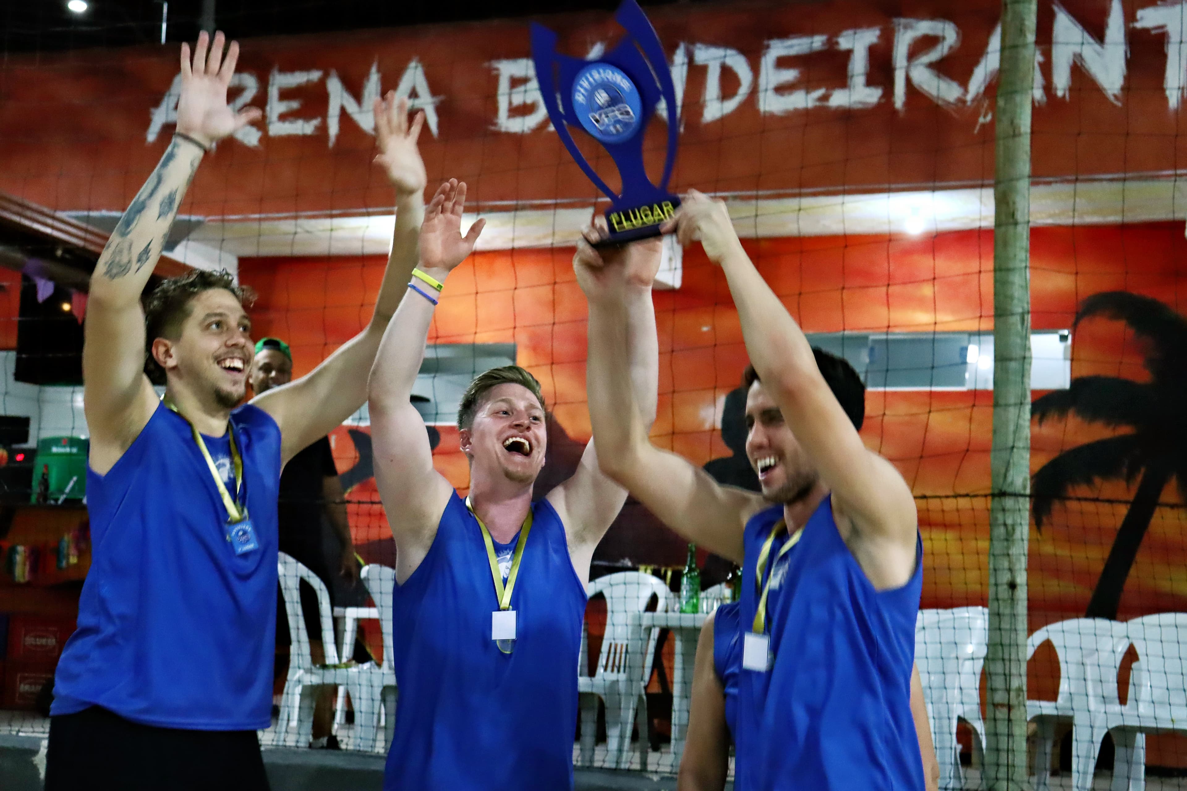 Atletas celebrando premiação em quadra de areia