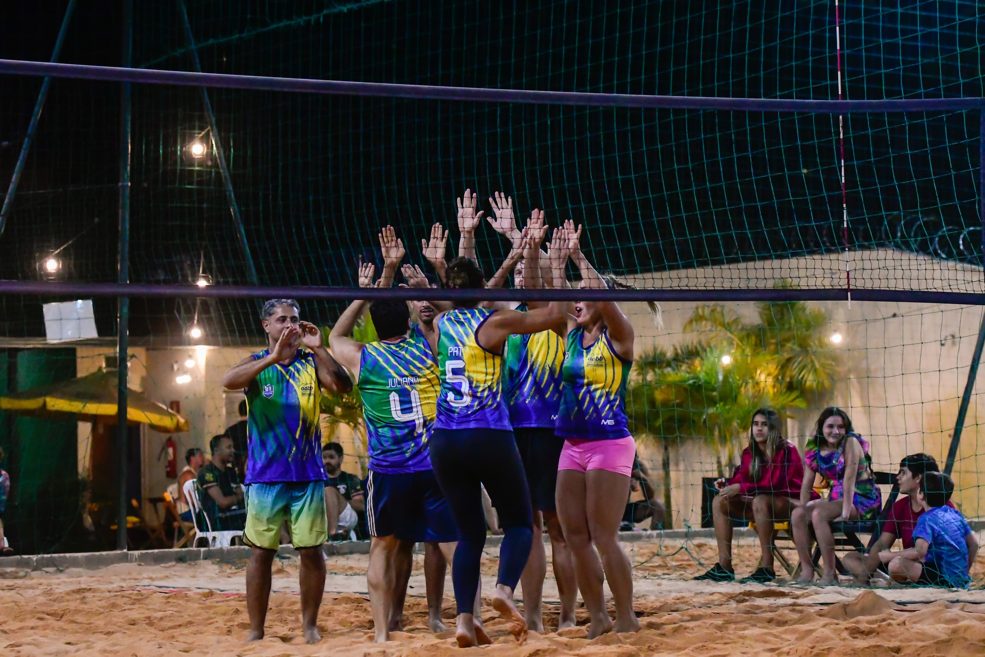 Atletas comemorando na rede durante jogo de areia do Ultimate Rivals